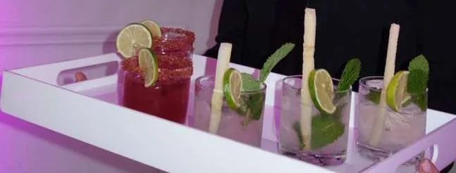 Mojito and margarita cocktails garnished with sugarcane sticks, mint and lime