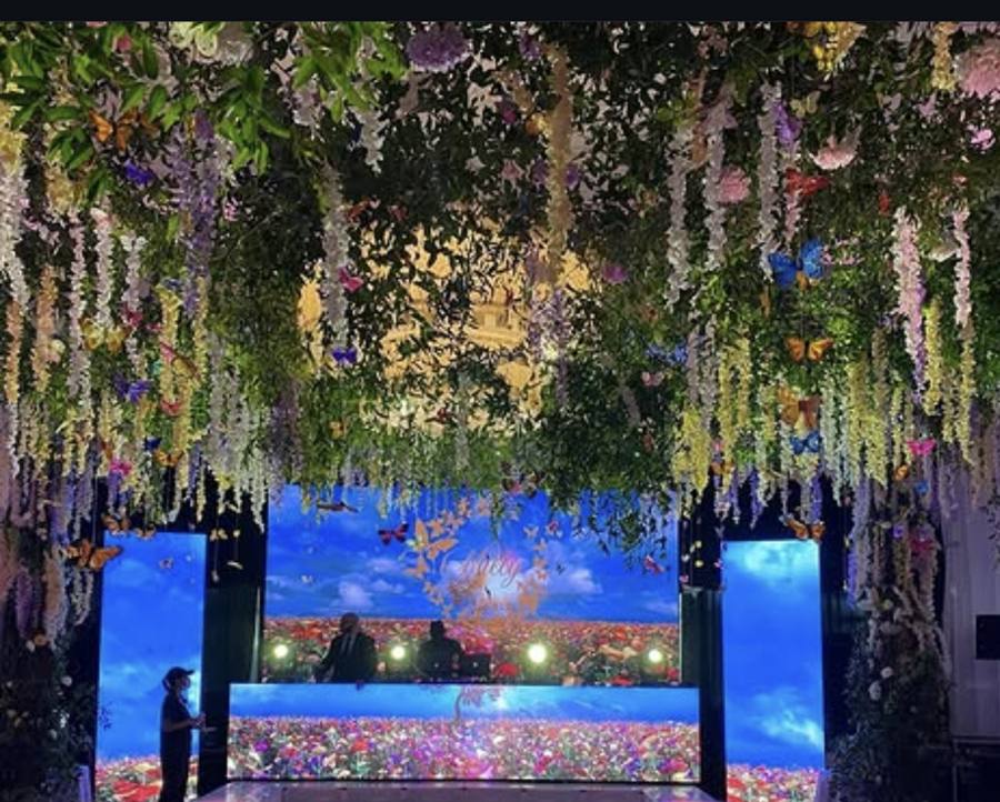 LED screens, stage and dance floor under a hanging floral canopy