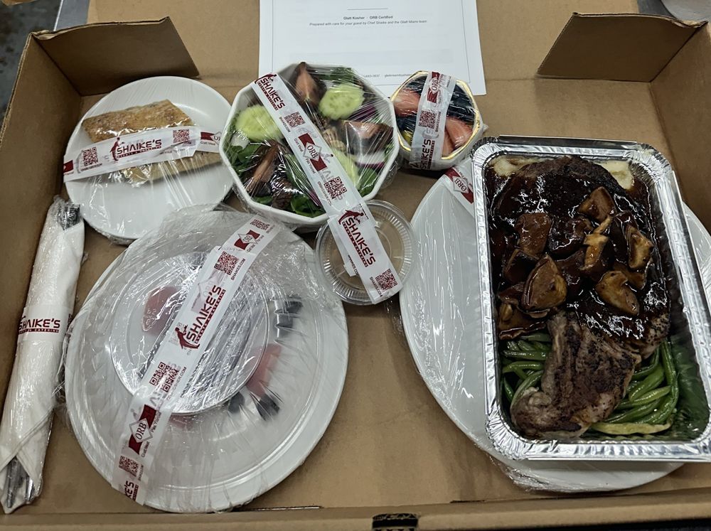 Individual kosher dinner box with salad, bread, prime rib with mushroom sauce and dessert, sealed with kosher tape